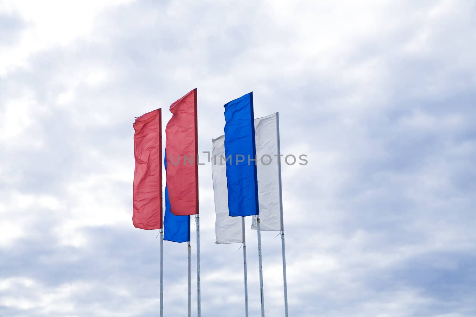 Flags of different colours against the cloudy sky