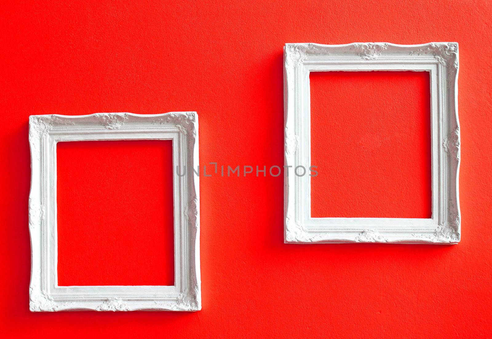 Two white vintage frames on red wall 