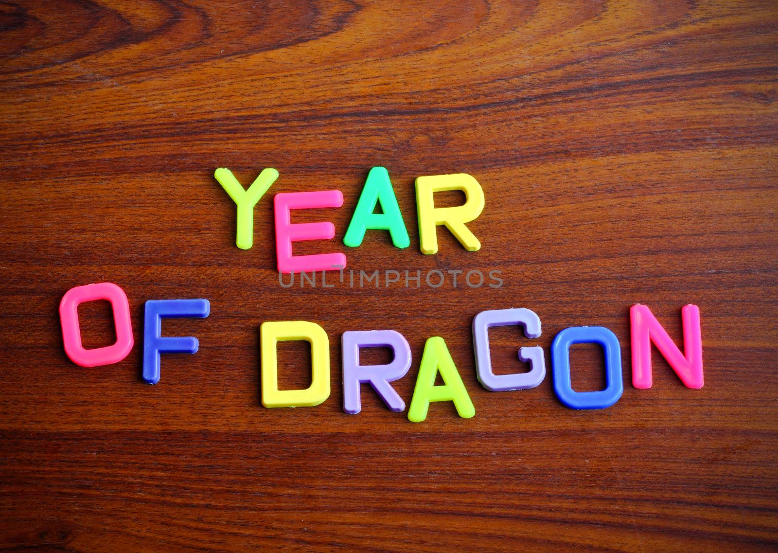 Year of dragon in colorful toy letters on wood background