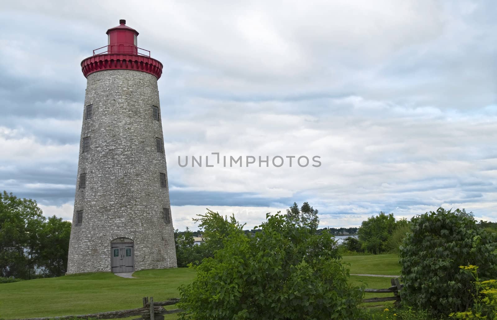 Country stone lighthouse surrounded by greenery.