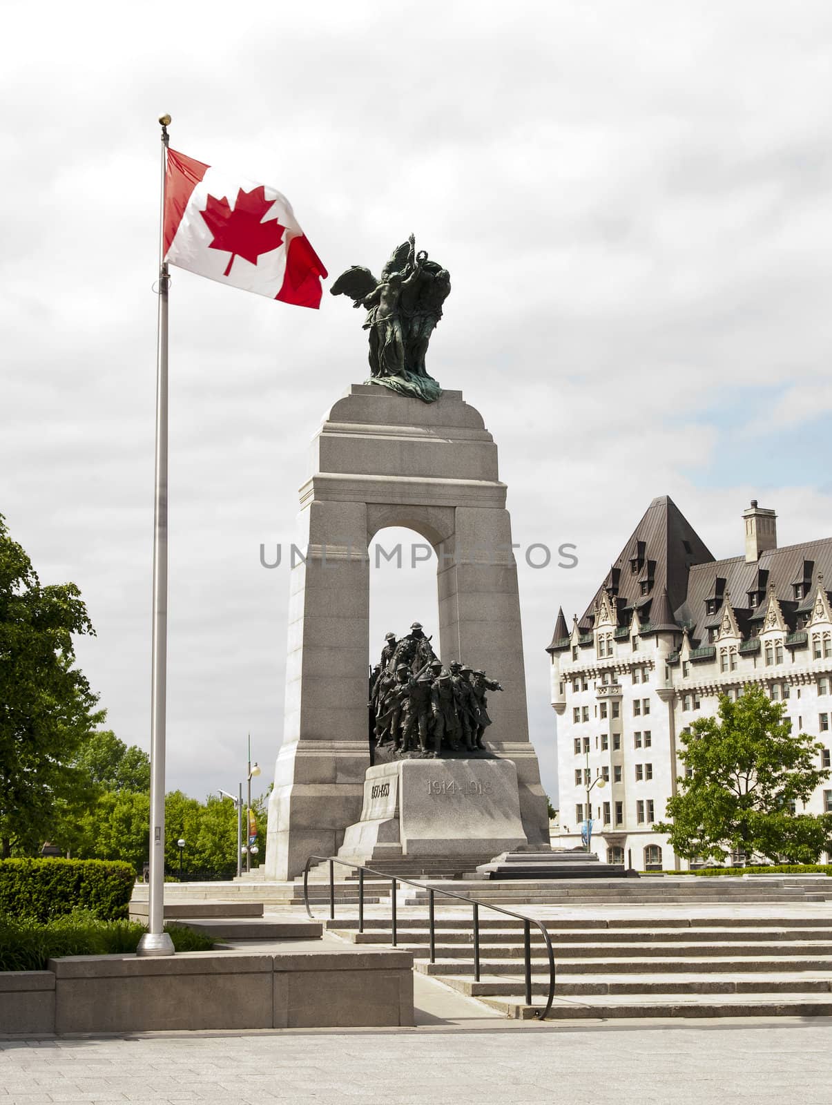 The National War Memorial with Canadian flag and the Fairmont Chateau Laurier in Ottawa, Canada.