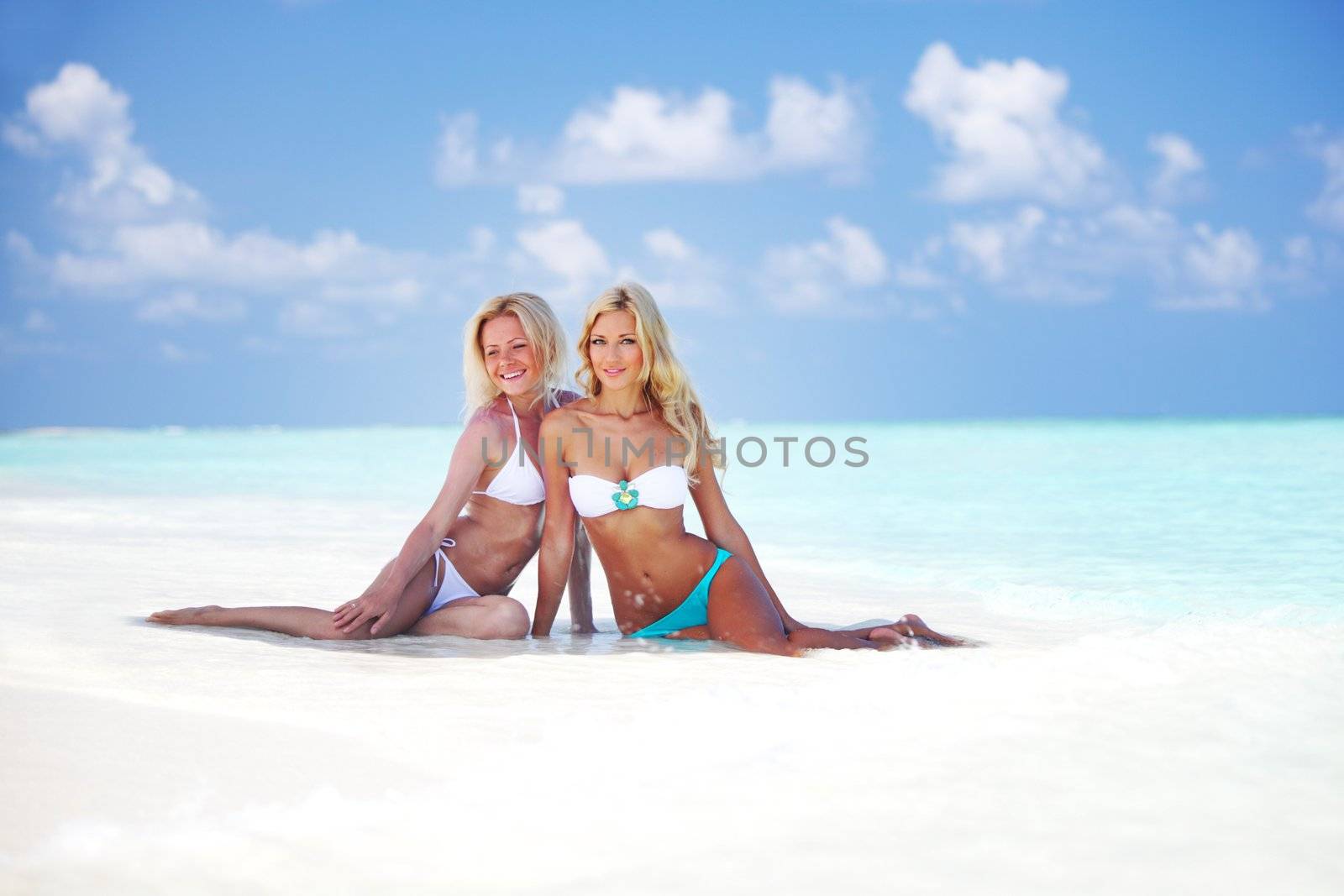 Two girls sitting on the ocean coast