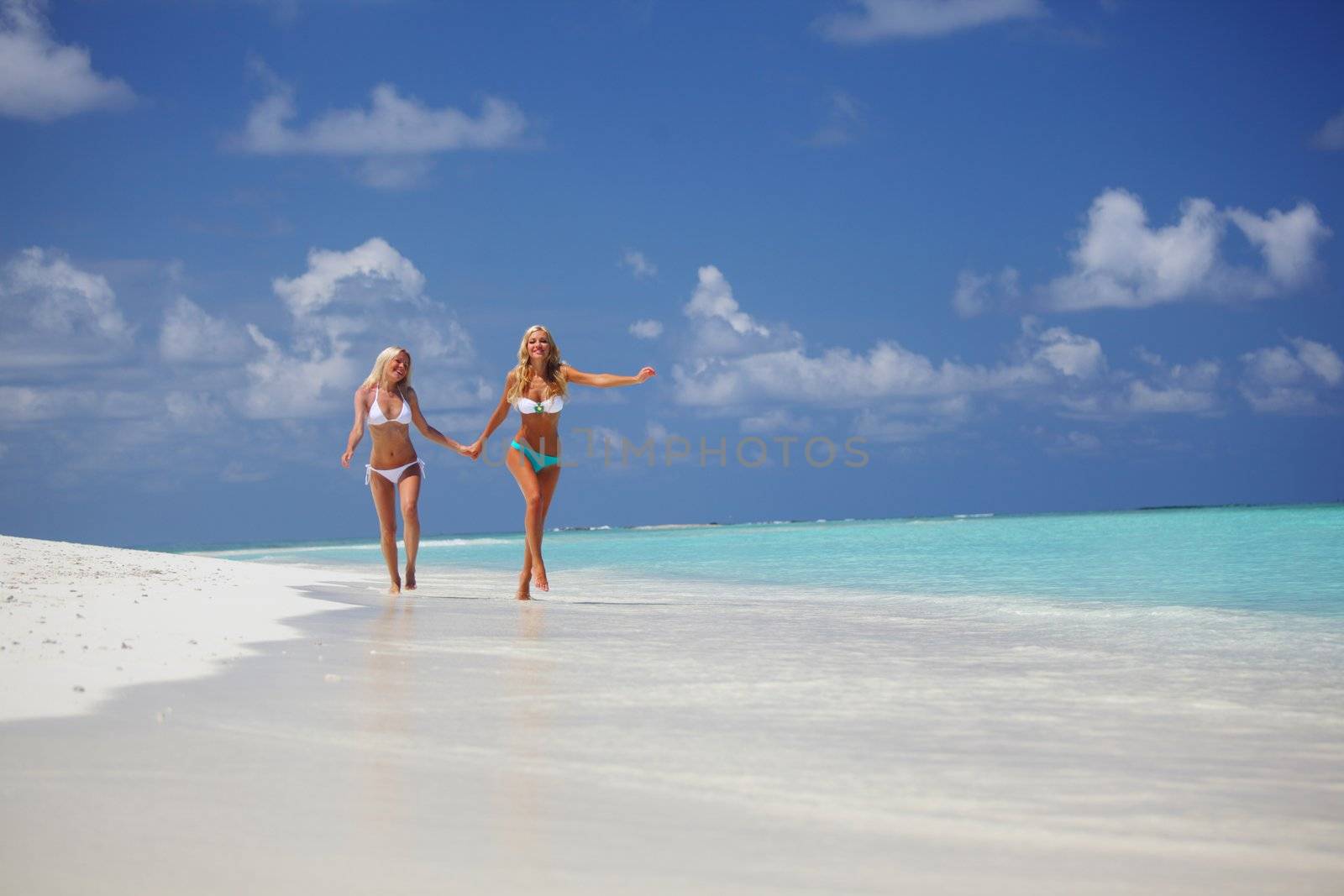 Two girls run along the ocean coast