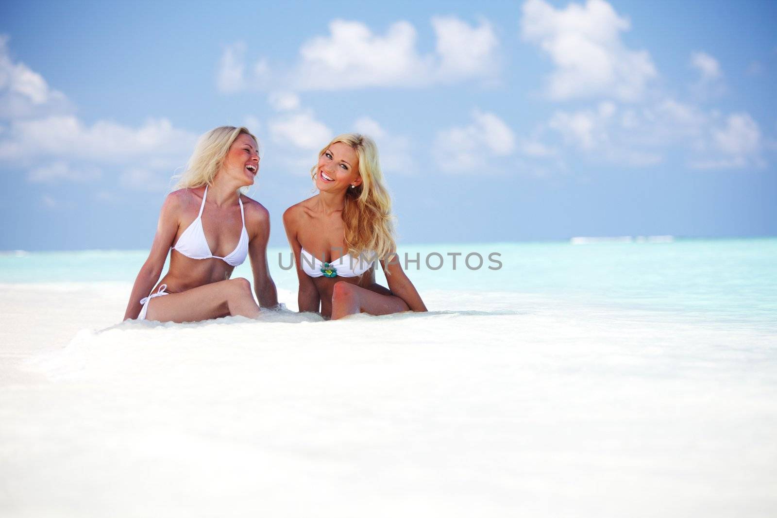 Two girls sitting on the ocean coast