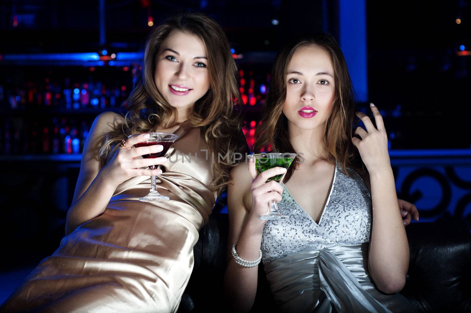 Young beautiful women, have a rest on a sofa and drink beverages