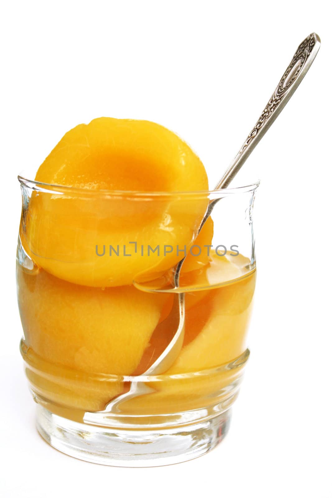 Halves of peaches in a sweet syrup in a glass isolated on the white

