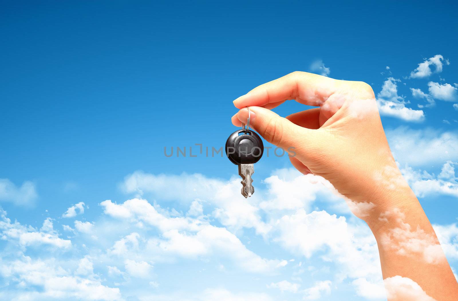 Woman's hand holding key with pretty sky background