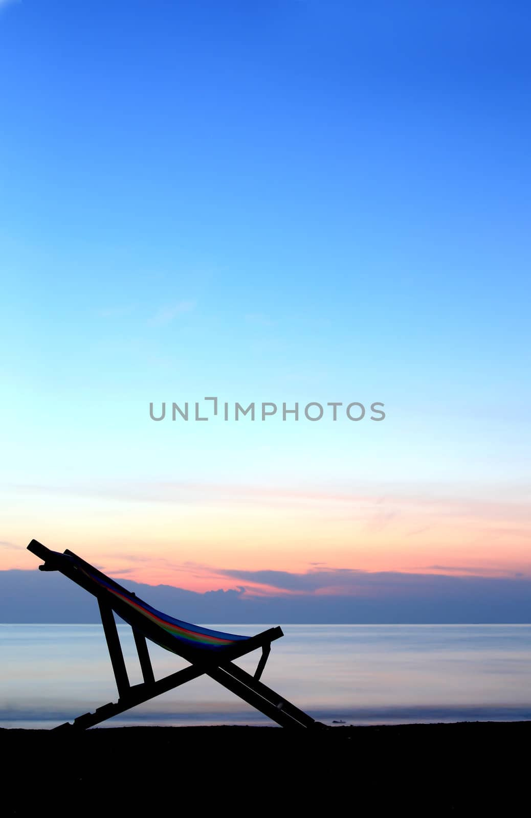 one deckchairs on beach at sunset