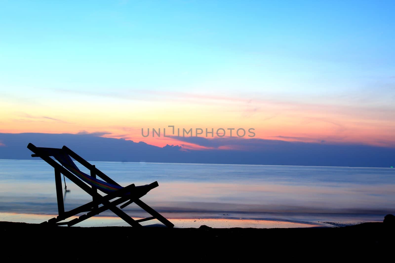 one deckchairs on beach at sunset