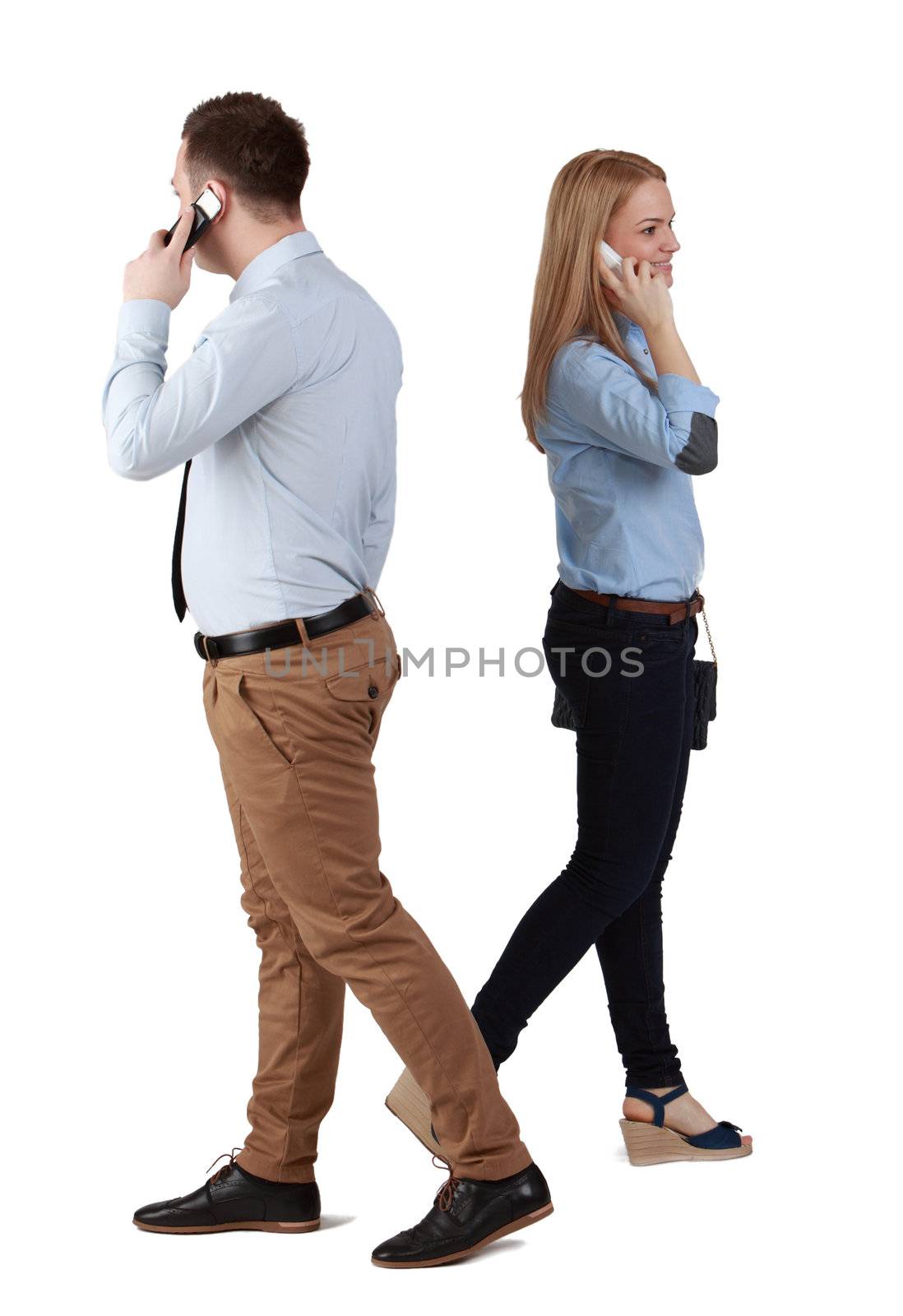 A man and a woman using mobile phones passing by themselves, against a white background.