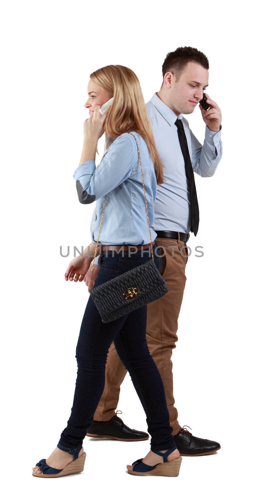 A man and a woman using mobile phones passing by themselves, against a white background.