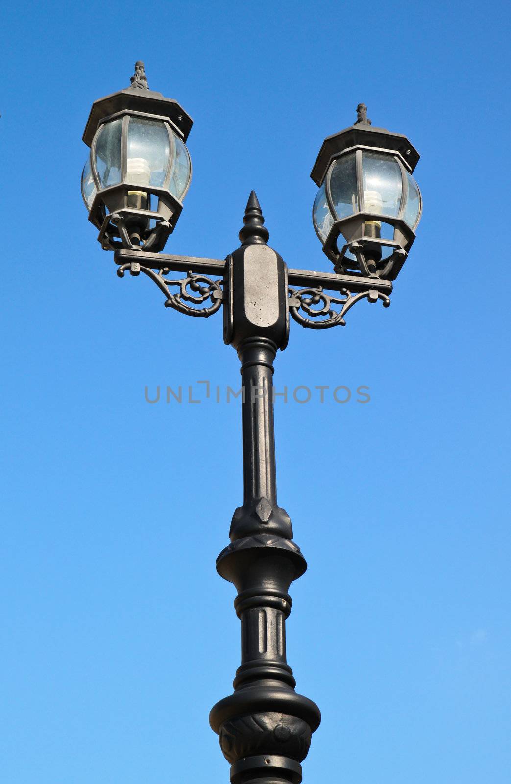 Old vintage street light against blue sky by nuchylee