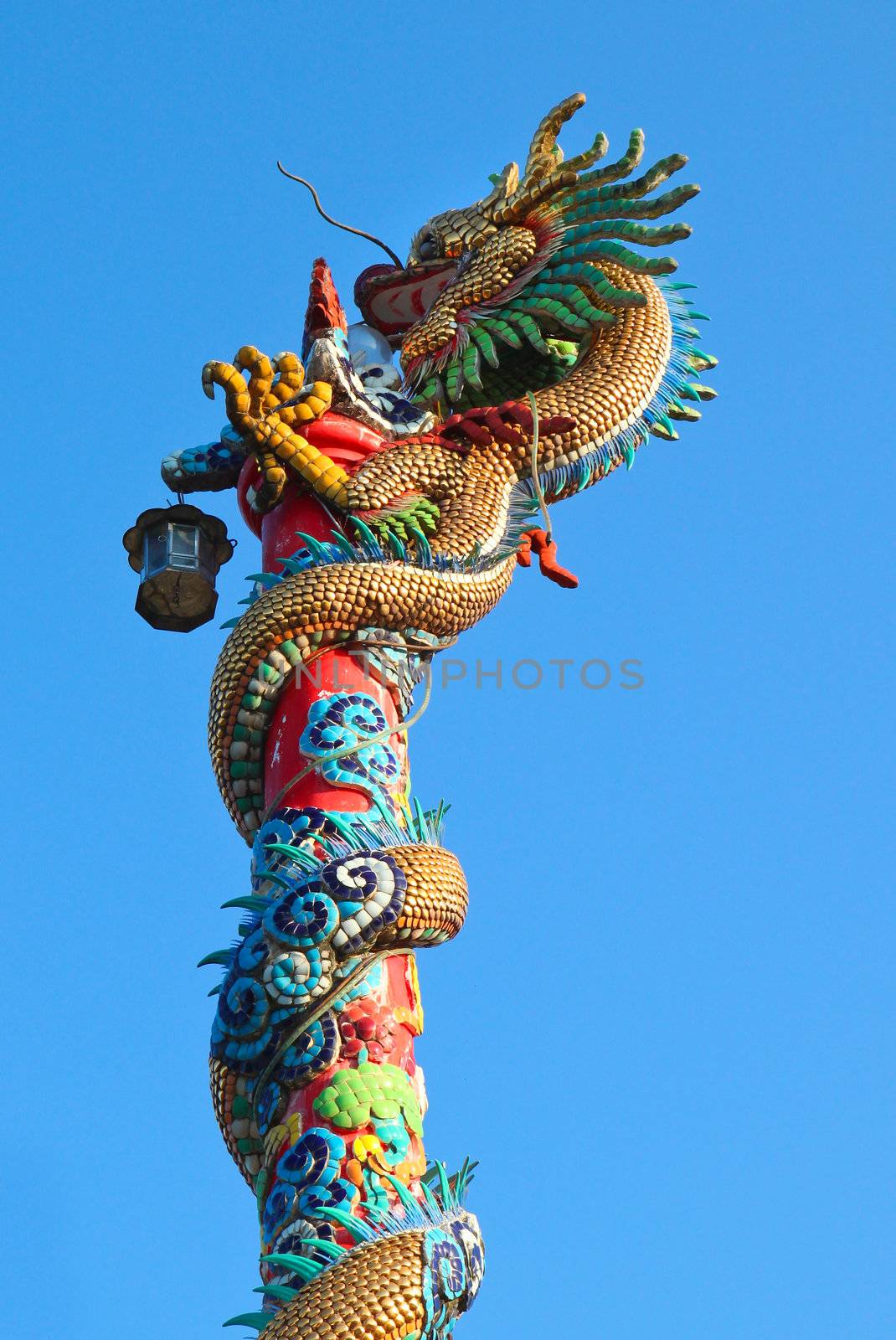 Golden dragon statue on red pillar against blue sky by nuchylee