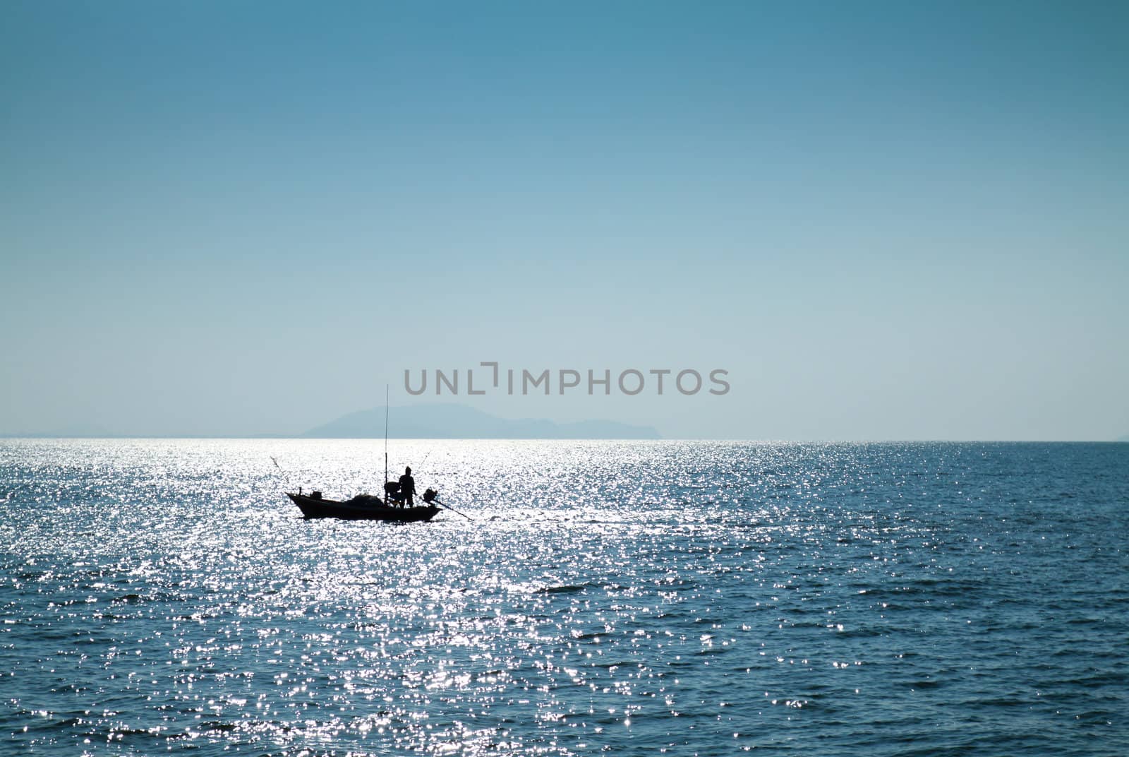The silhouette of a fisherman with his boat in the sea by nuchylee