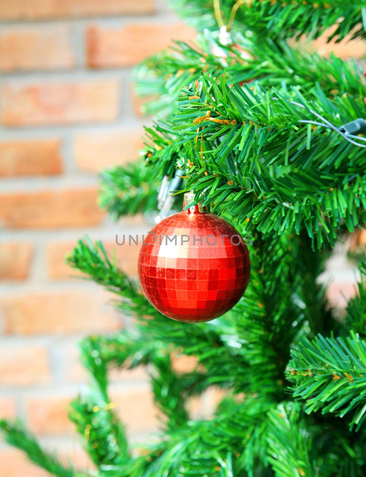 Christmas tree with red ball and brick wall