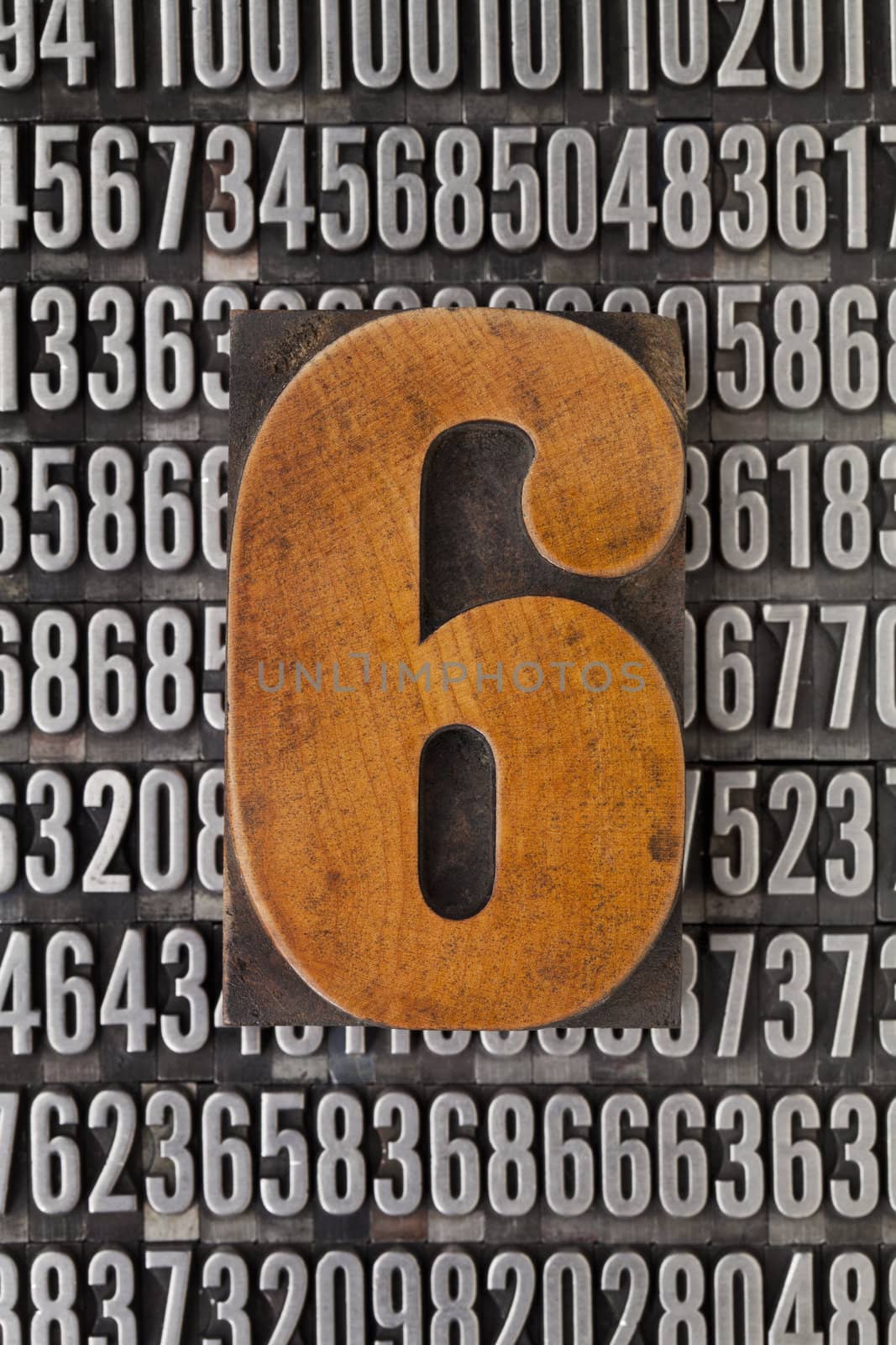 number six in vintage letterpress wood type against background of random metal numbers