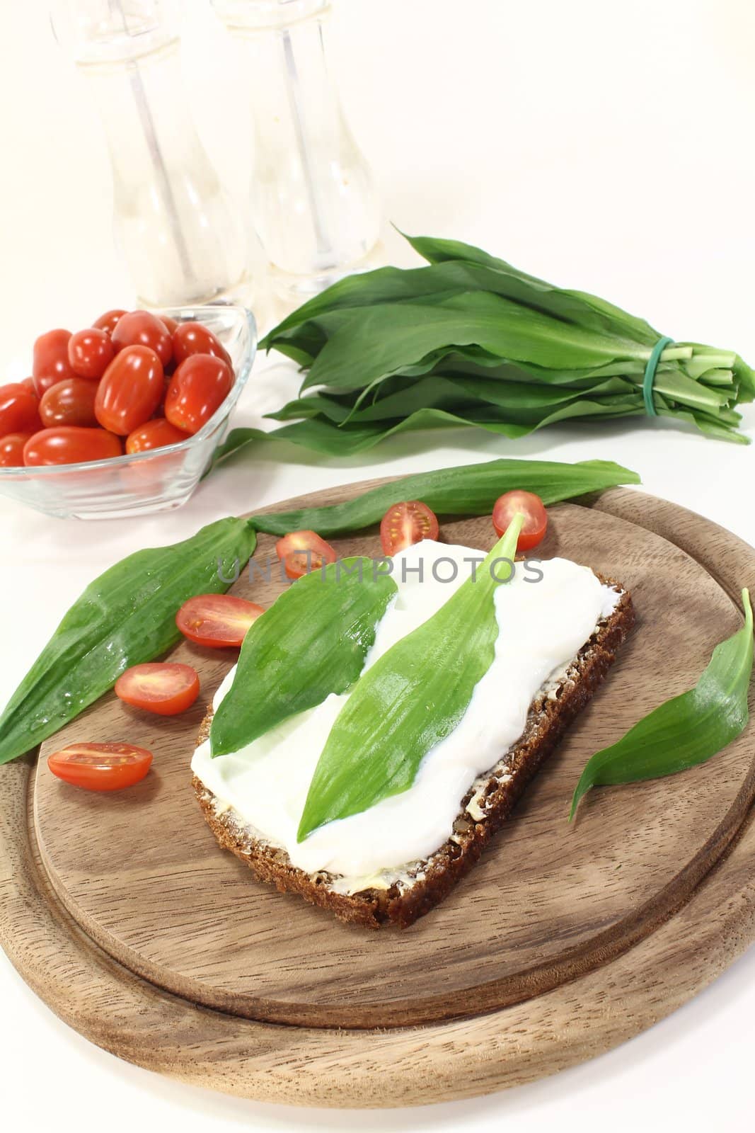 Slice of bread with fresh cottage cheese, ramson and chopped tomatoes on a light background