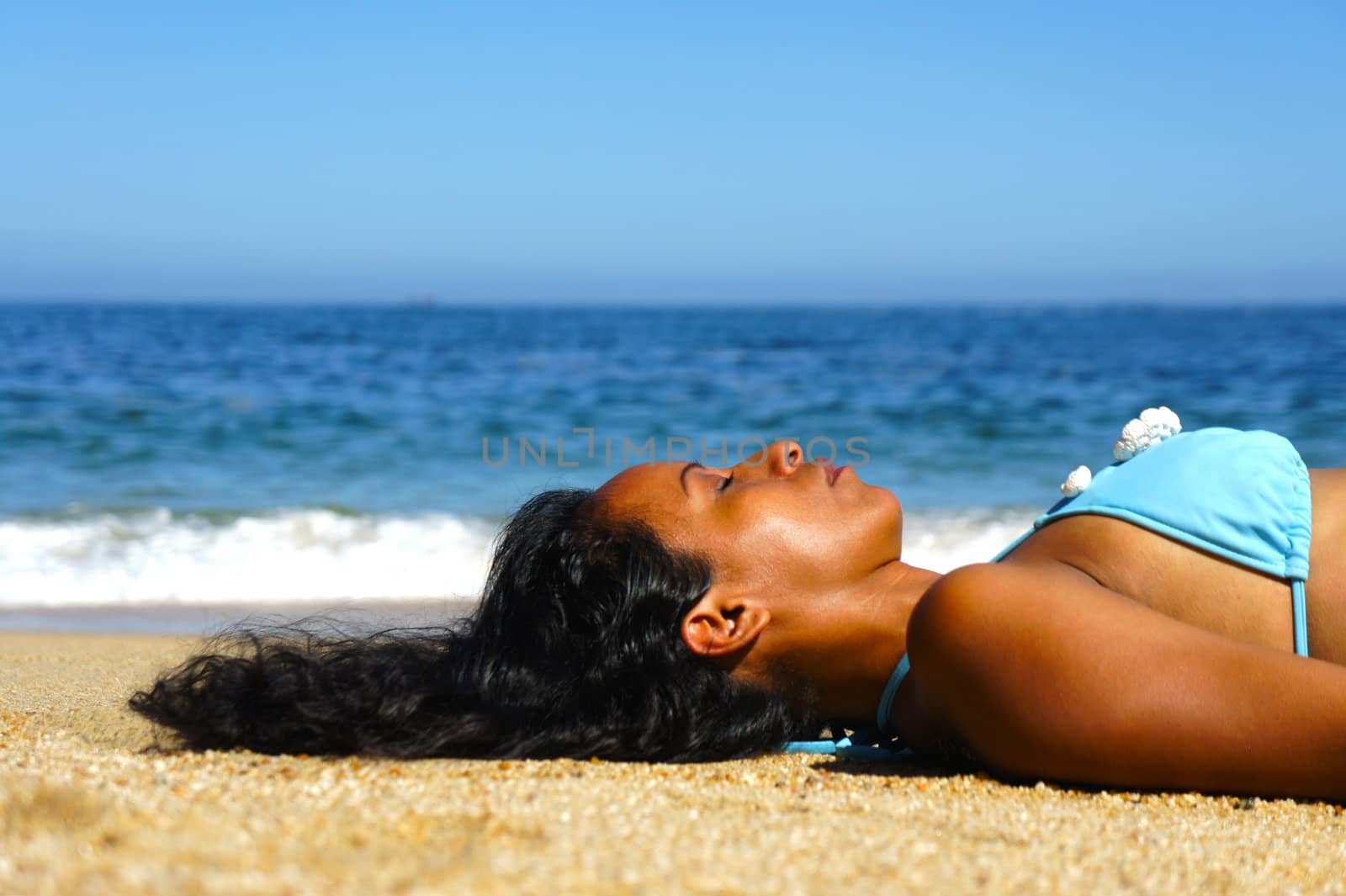 Young woman laying on beach sun tanning.