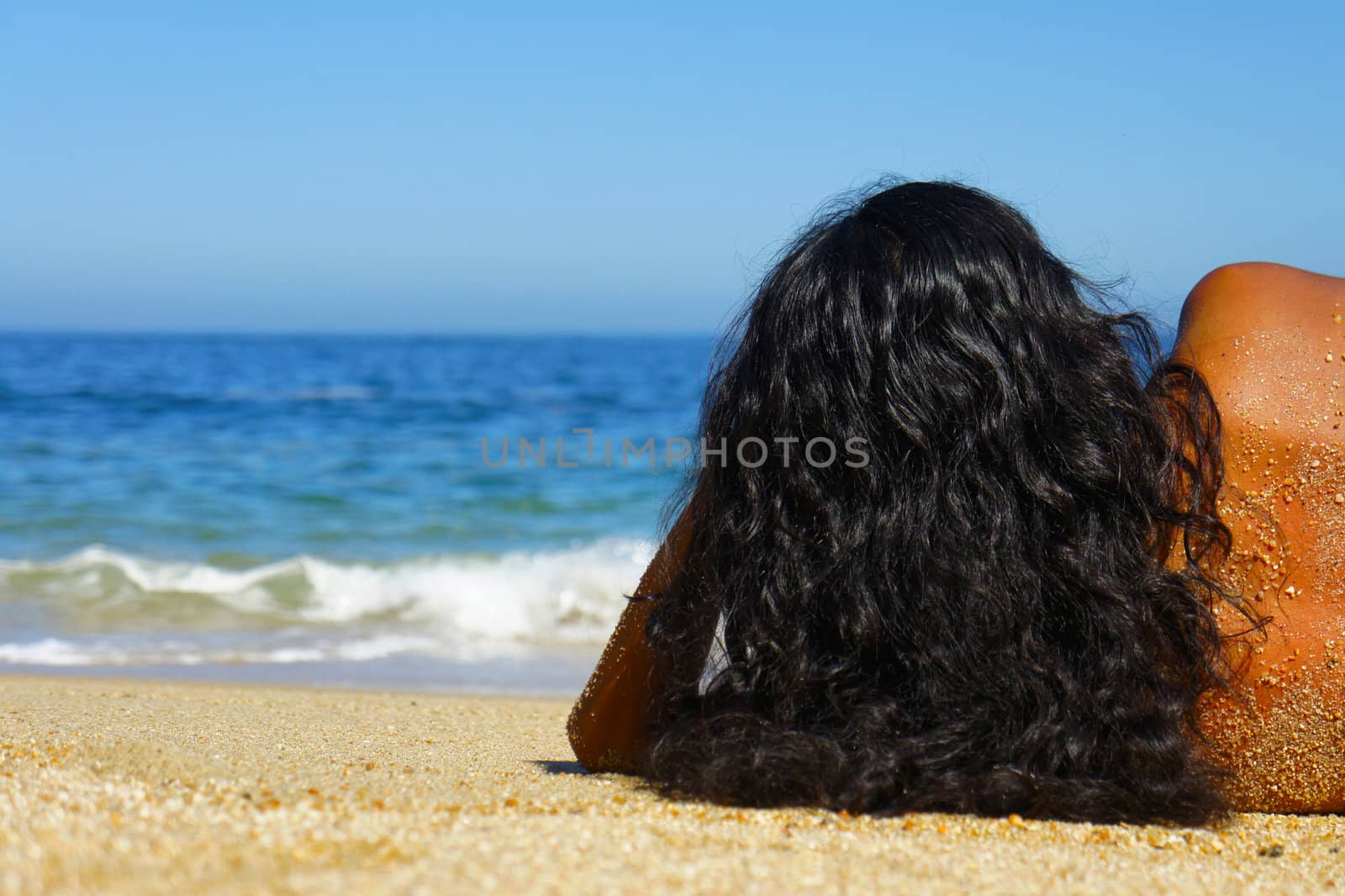 Young woman laying on beach sun tanning.