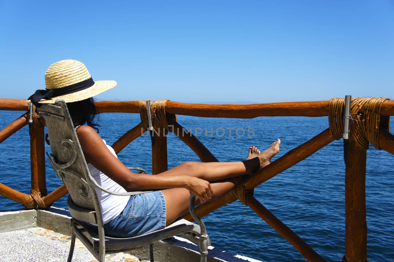 Young woman sitting on a balcony looking over the ocean enjoying the view