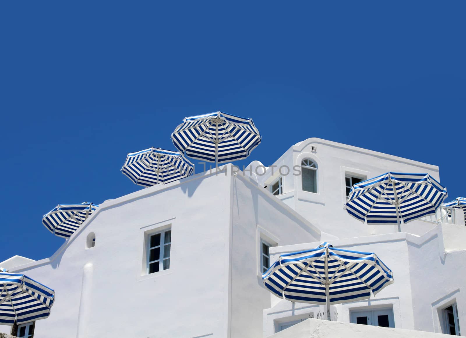 Sunshade umbrellas on white holiday apartment balcony blue sky background