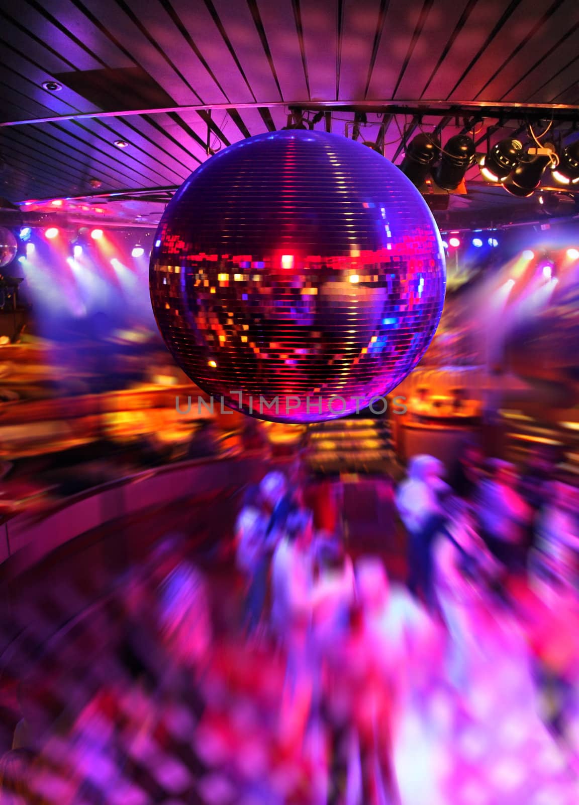 People dancing under colorful lights of disco mirror ball