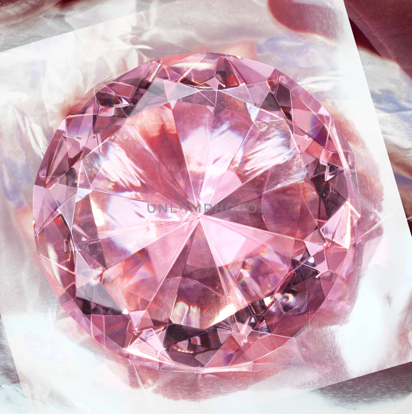 Pink gemstone diamond shining on reflective background