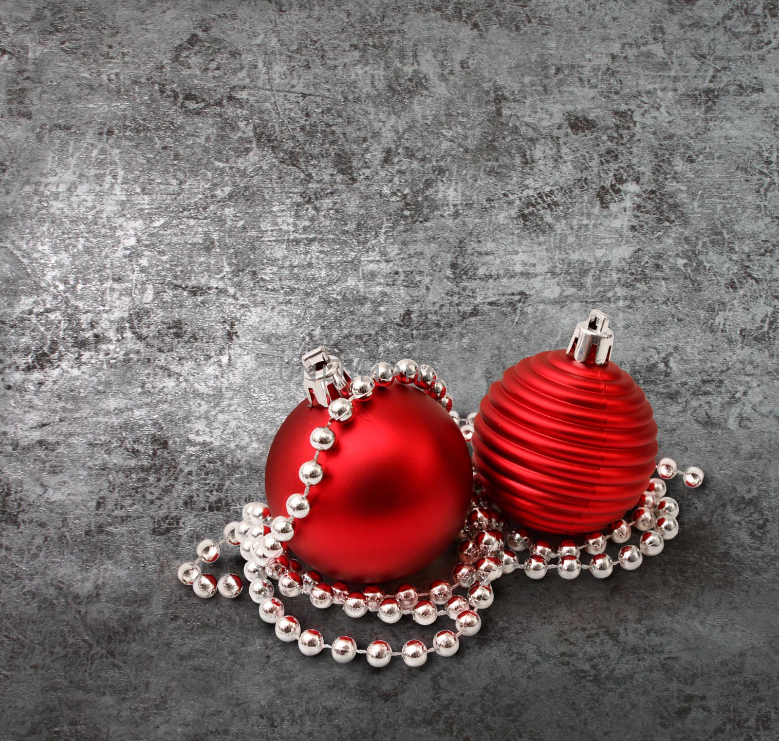 Red christmas decoration glass balls and pearls on textured silver background
