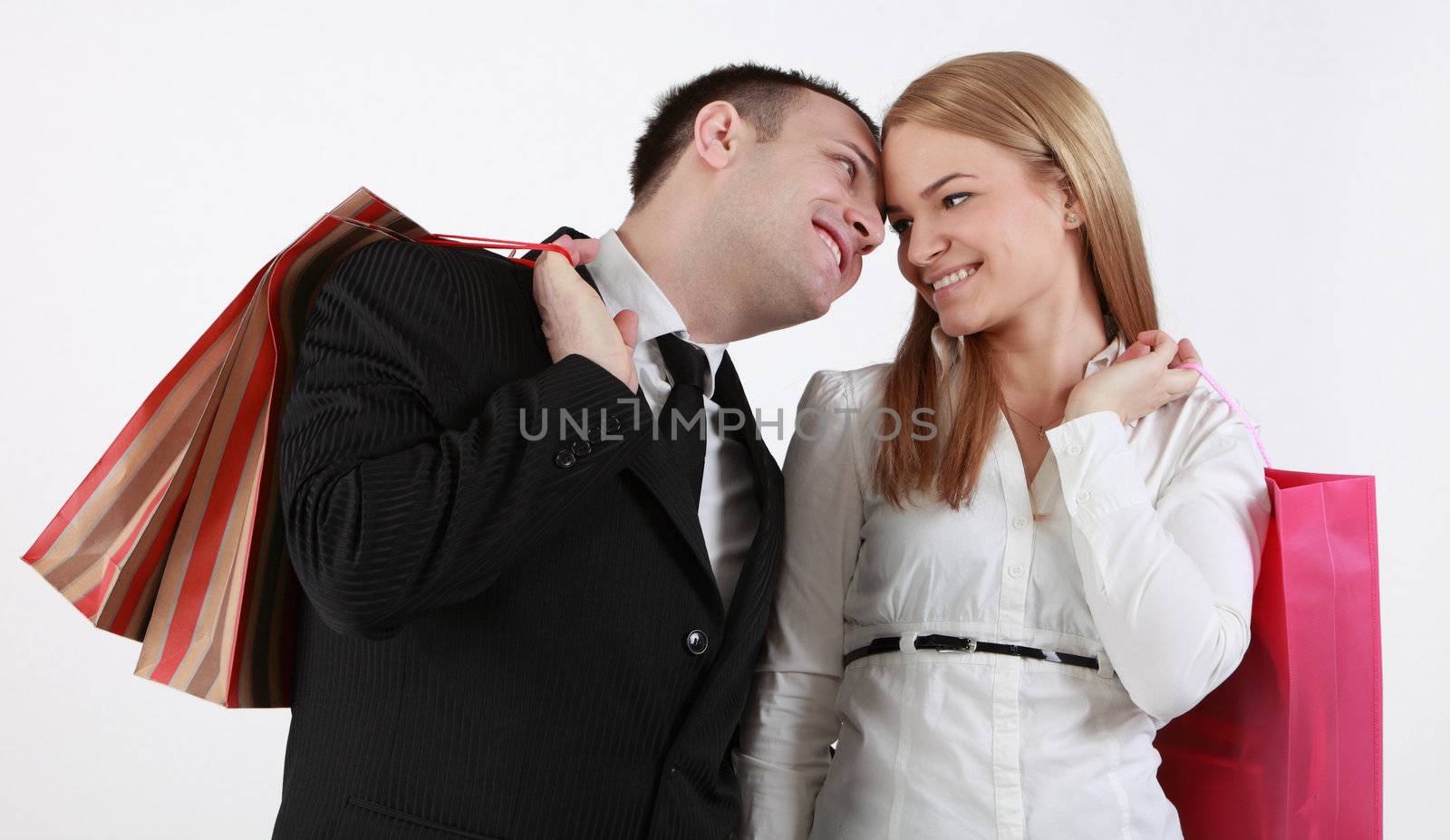 Happy couple with shopping bags against a white background.