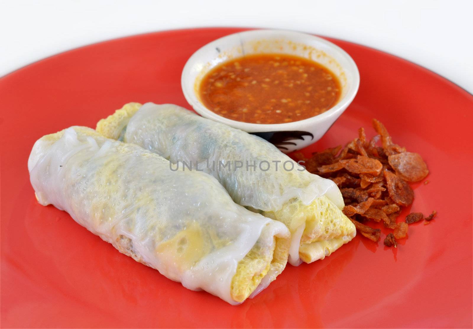 Vietnamese rice noodle rolls with a filling of pork sliced and egg ,  fried onion on red dish