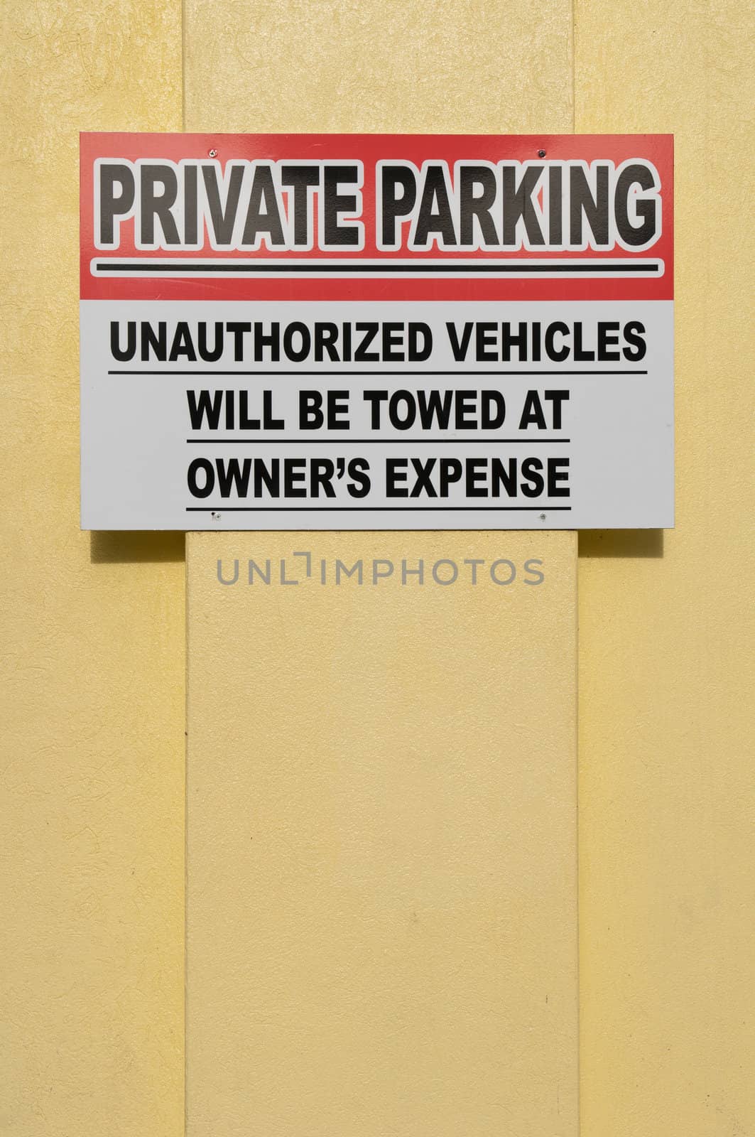private parking sign hanging on a yellow wall