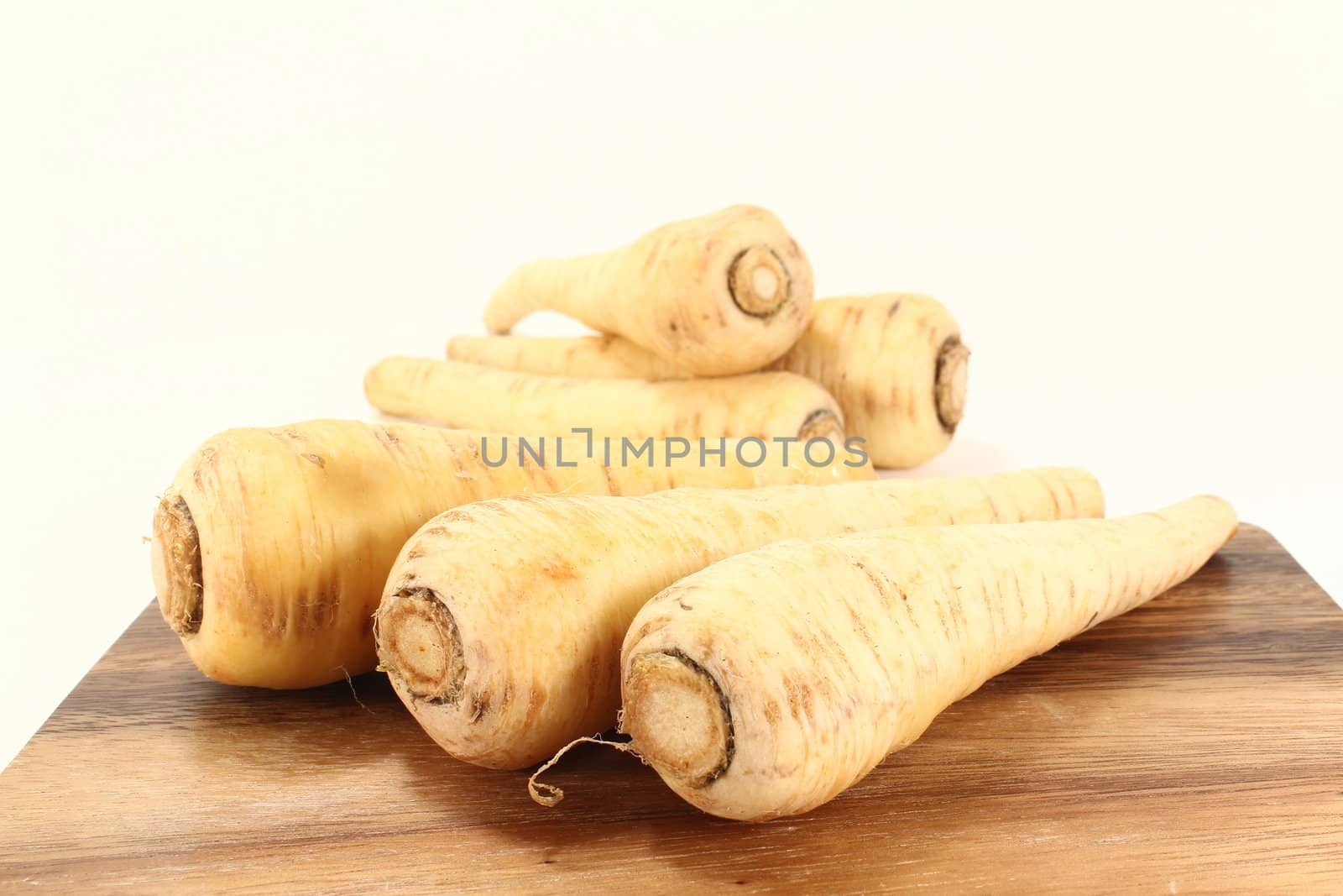 raw parsnips on a wooden board on light background