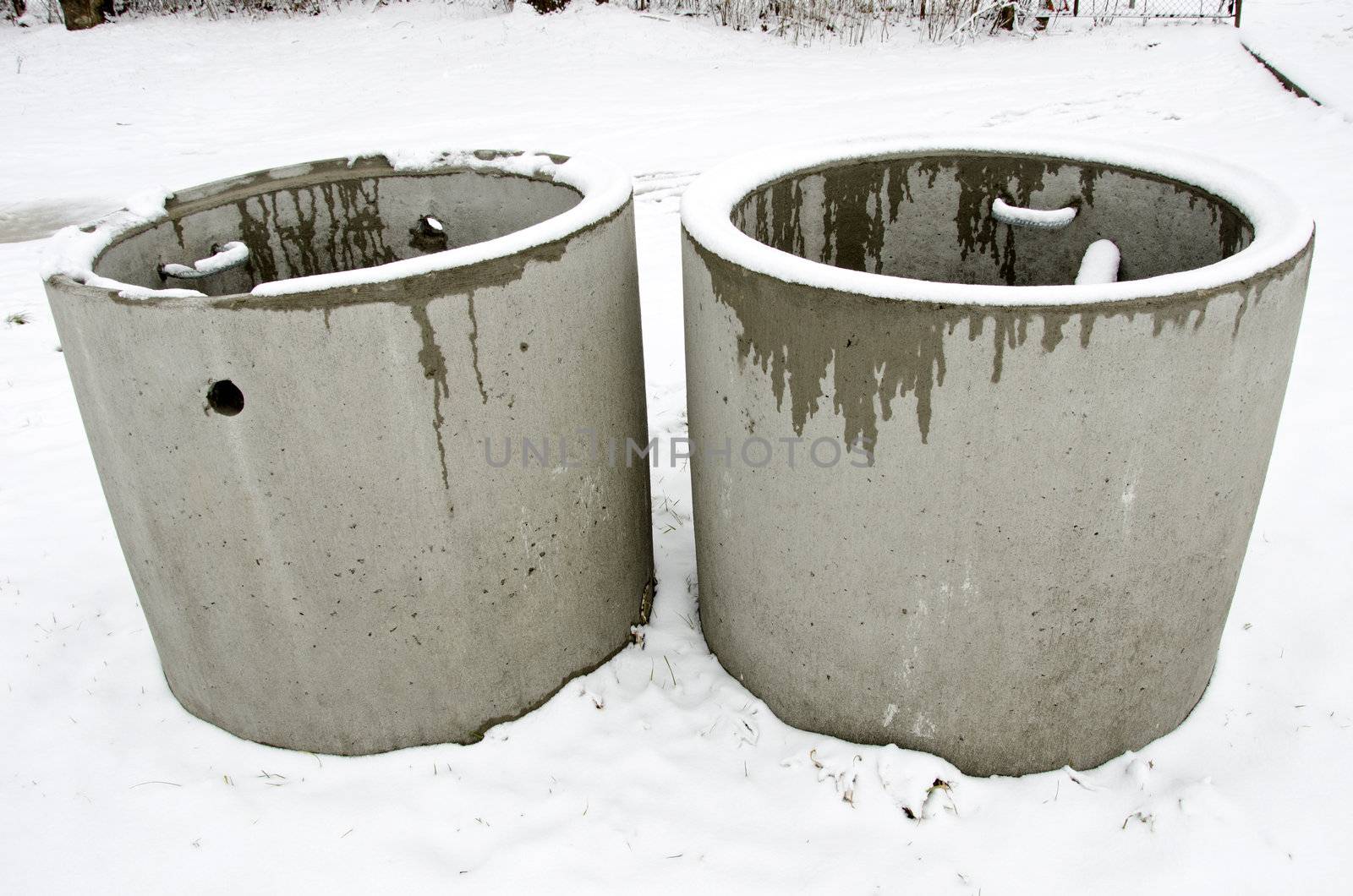 Concrete manholes with ladder protruding from ground in winter. Urban waste water treatment system.