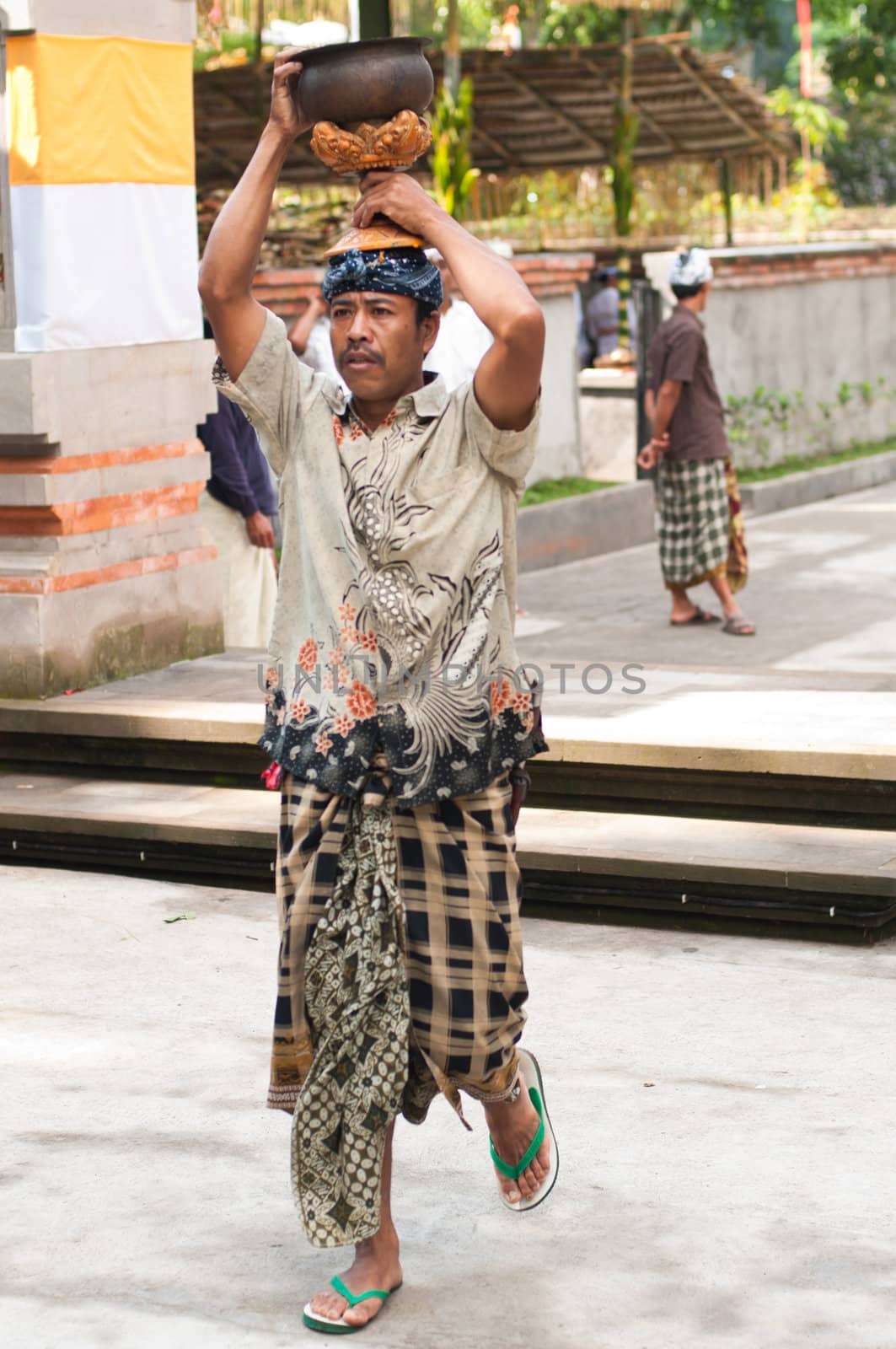 Balinese Man Carrying Offerings On His Head by nvelichko