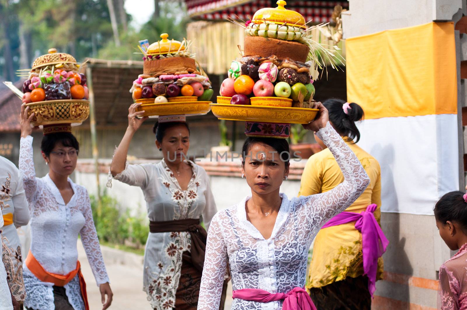 Balinese Woman Carrying Offerings On Her Head by nvelichko