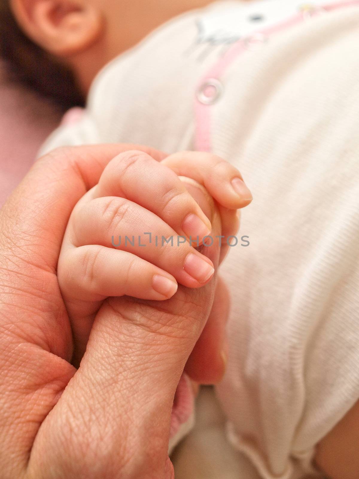 Parent holding an infants hand, small hand towards big
