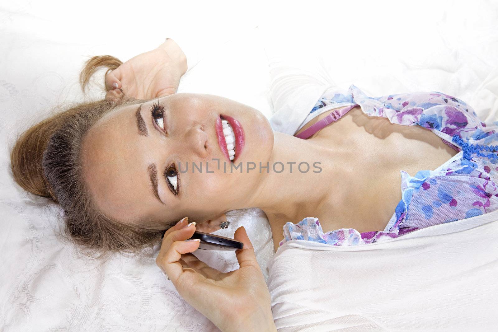 Pretty woman lying on the bed holding her smartphone