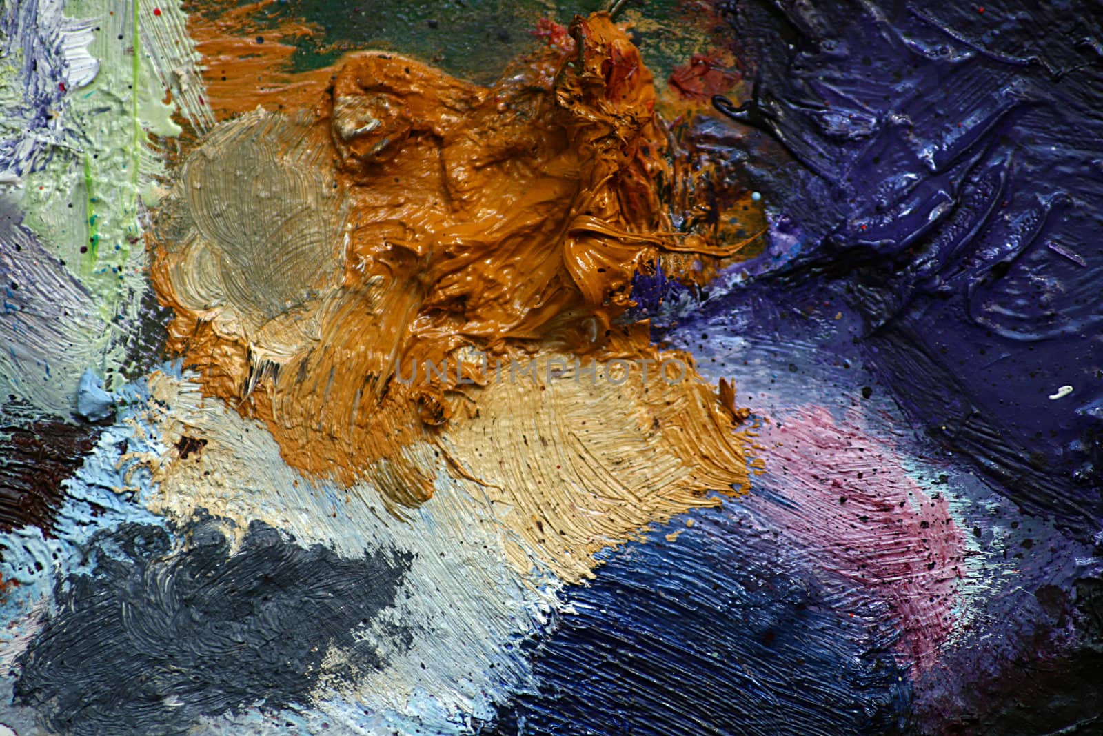 Close up detail of an artists pallet with oil paints creating an abstract pattern background, set on a landscape format.