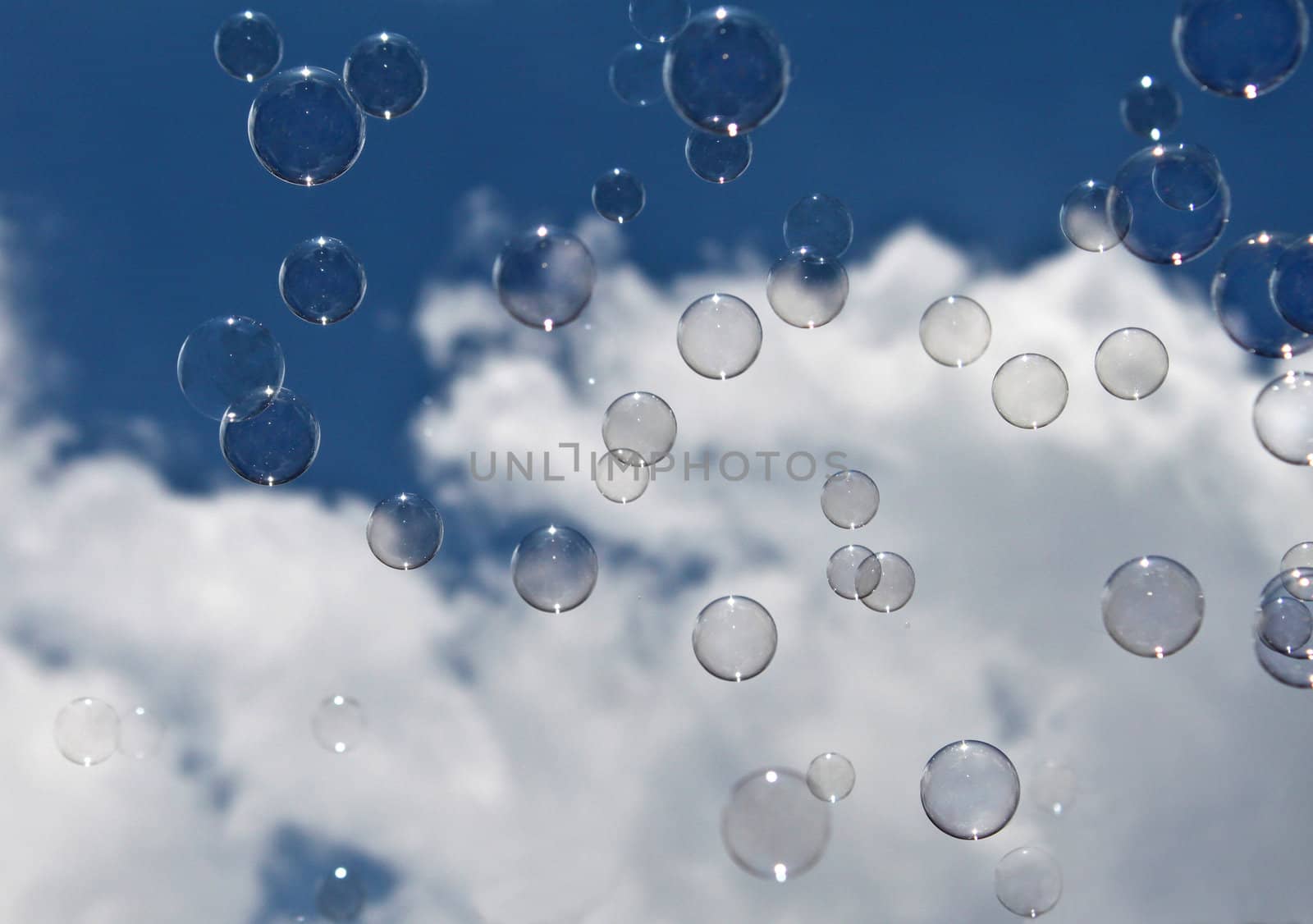 Bubbles flying in the sky passing the white clouds