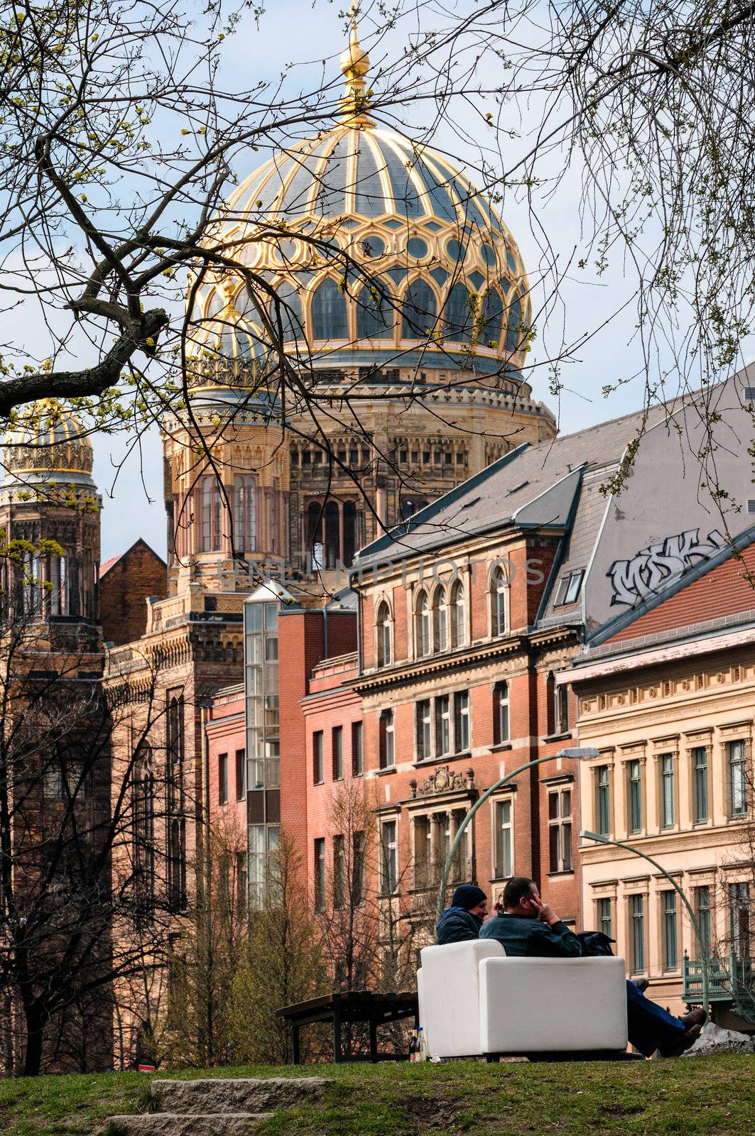 Two people having a conversation on a couch in a park located in the centre of Berlin (Mitte Scheunenviertel).