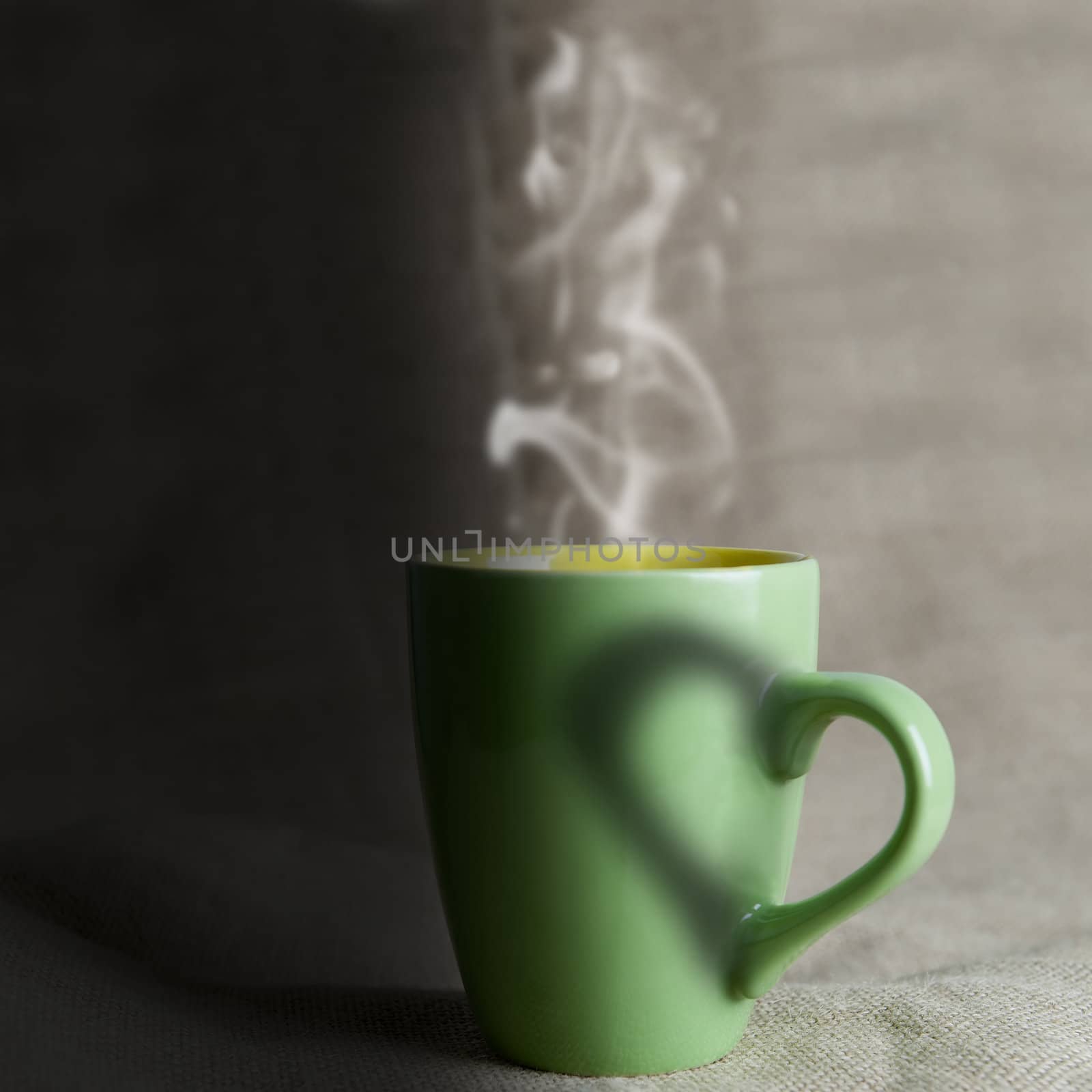 A green mug with hot coffee and a heart.