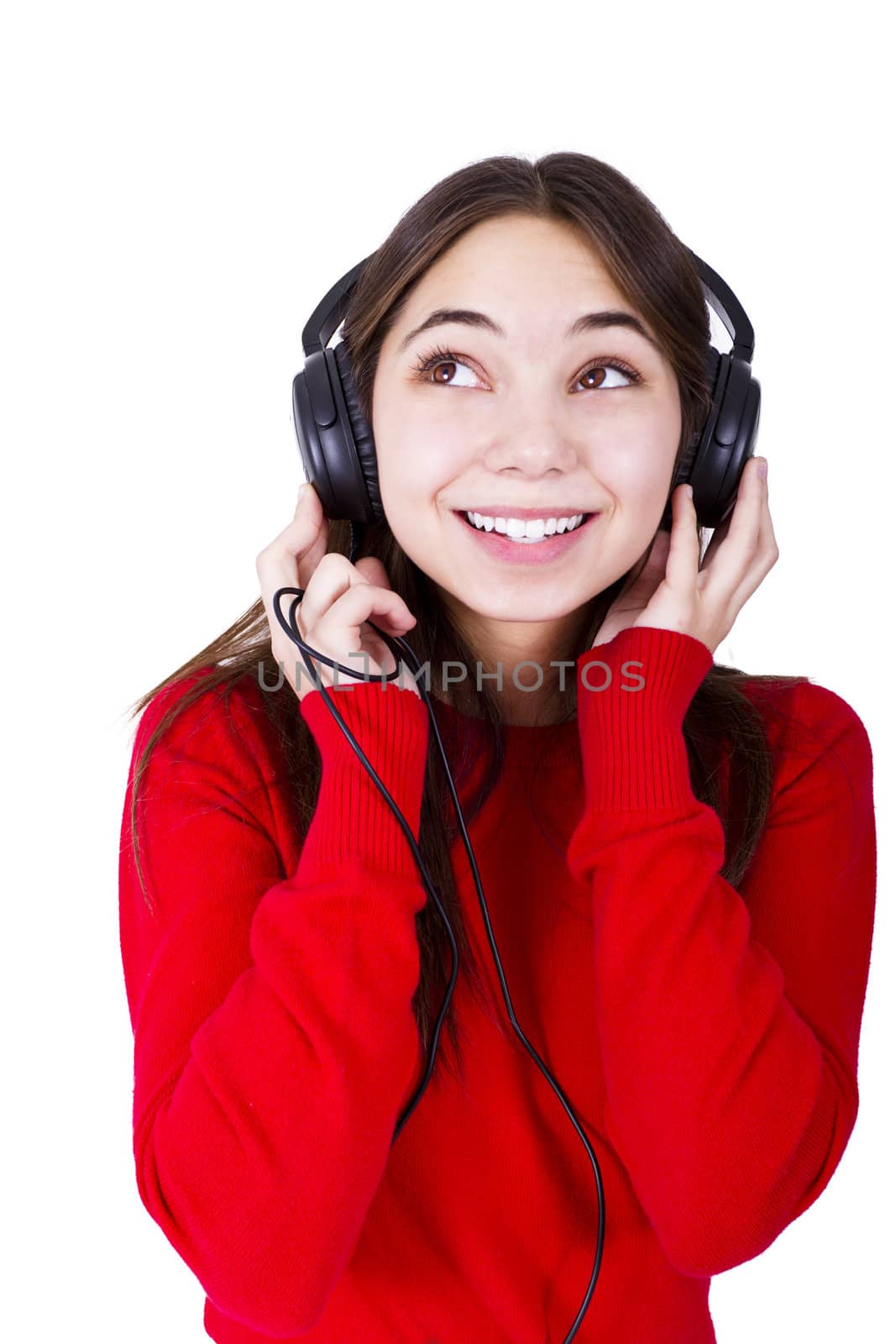Teenager girl listening music in headphones, looking up to something. She is wearing catchy red clothing relaxed. Isolated on white background.
