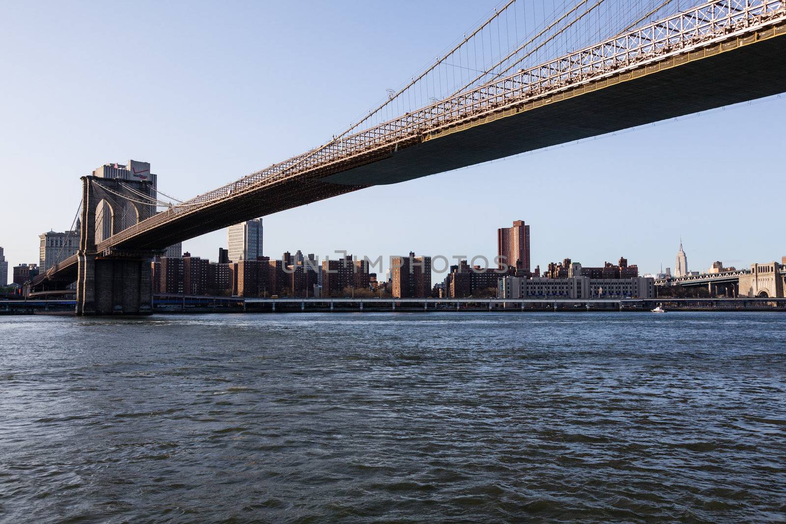 Empire State Tower visible under span of Brooklyn bridge in NY