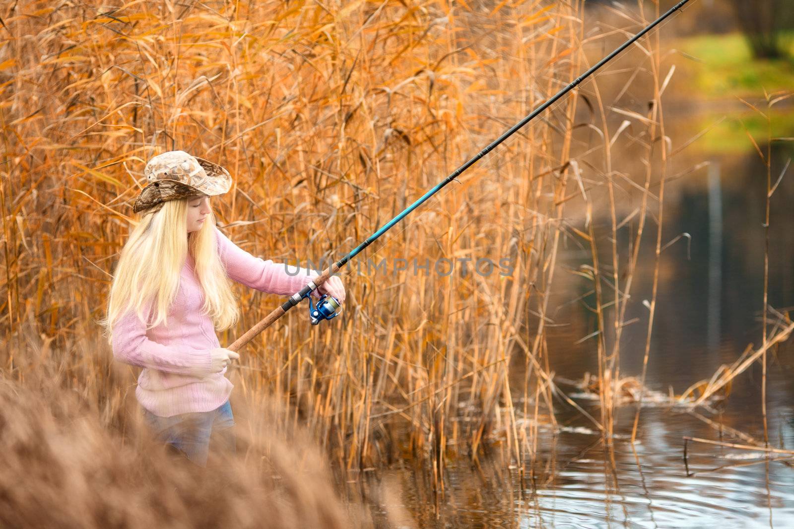 beautiful blond girl in pink sweater fishing