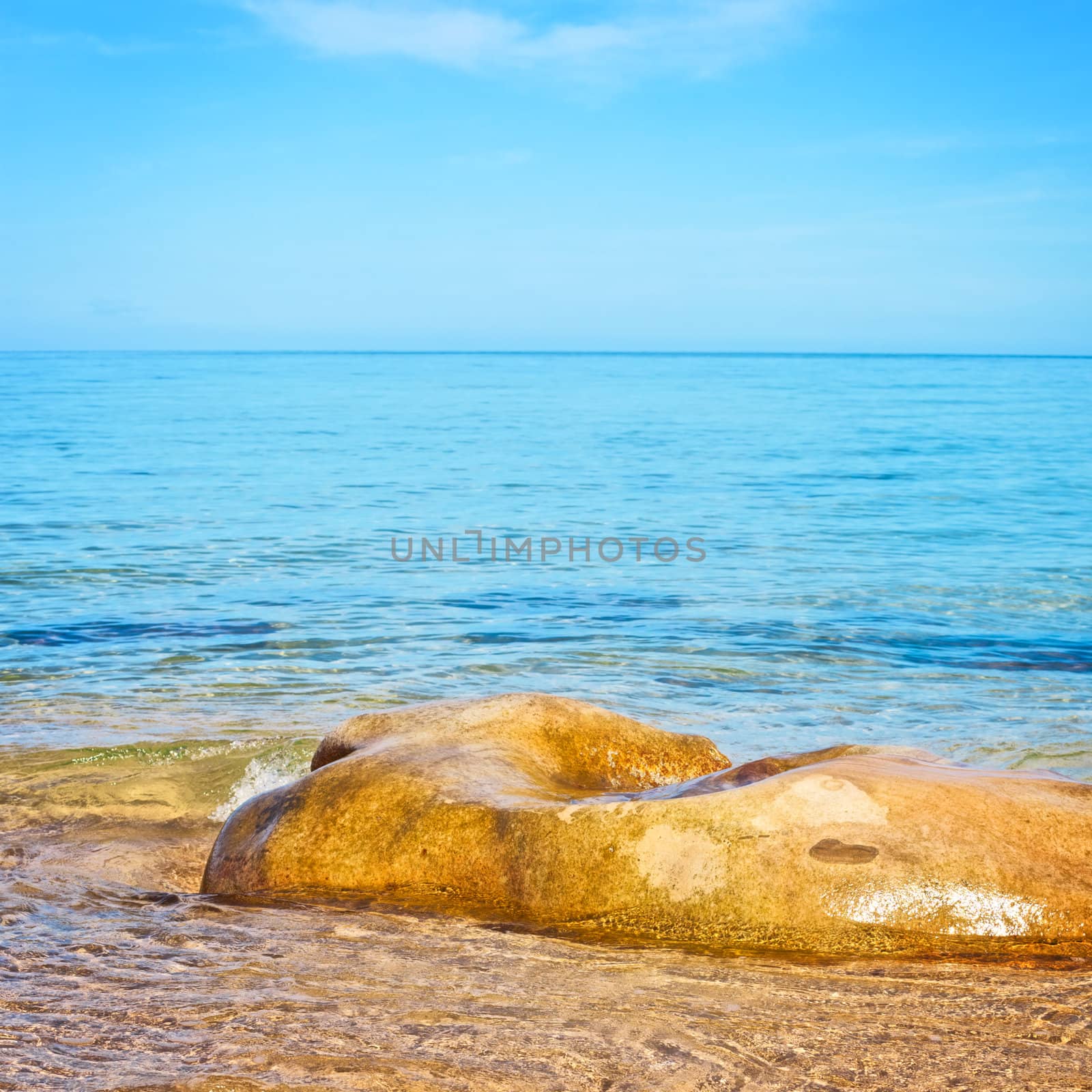transparent sea with big stone at sunny day