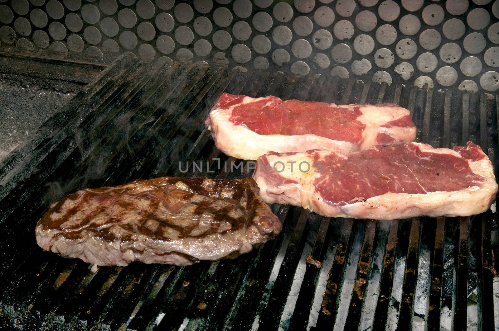 cooking beef steaks on the grill in the restaurant