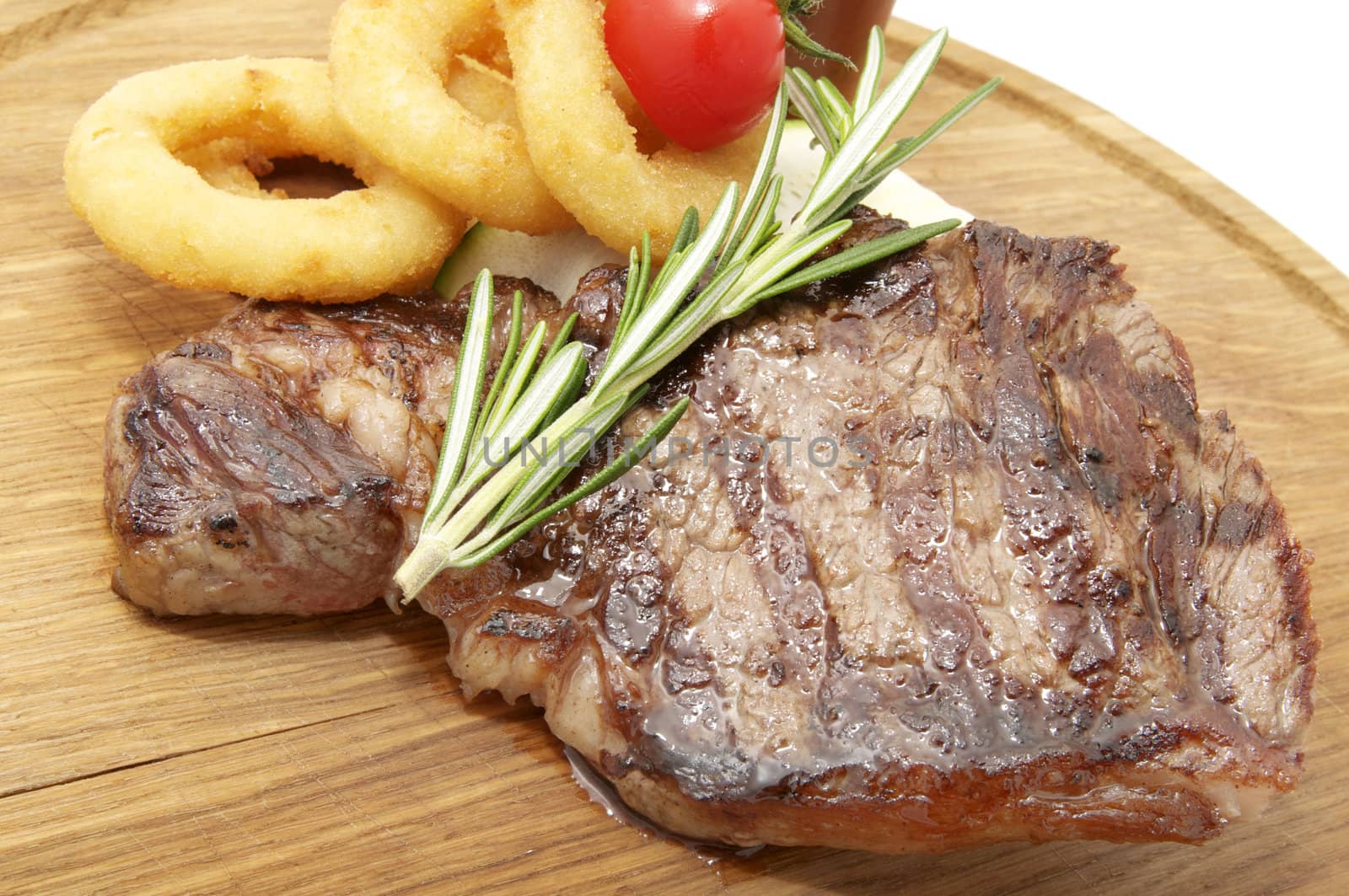 juicy beef steak and onion rings on a wooden platter