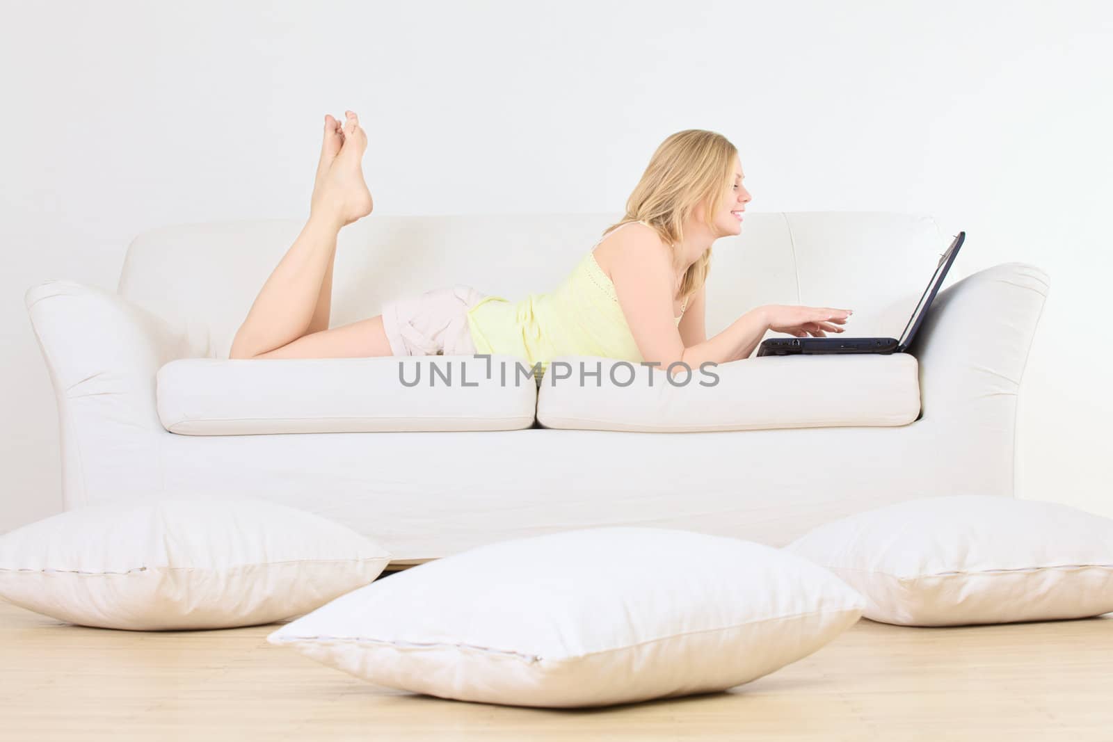 charming woman lying on a sofa with laptop