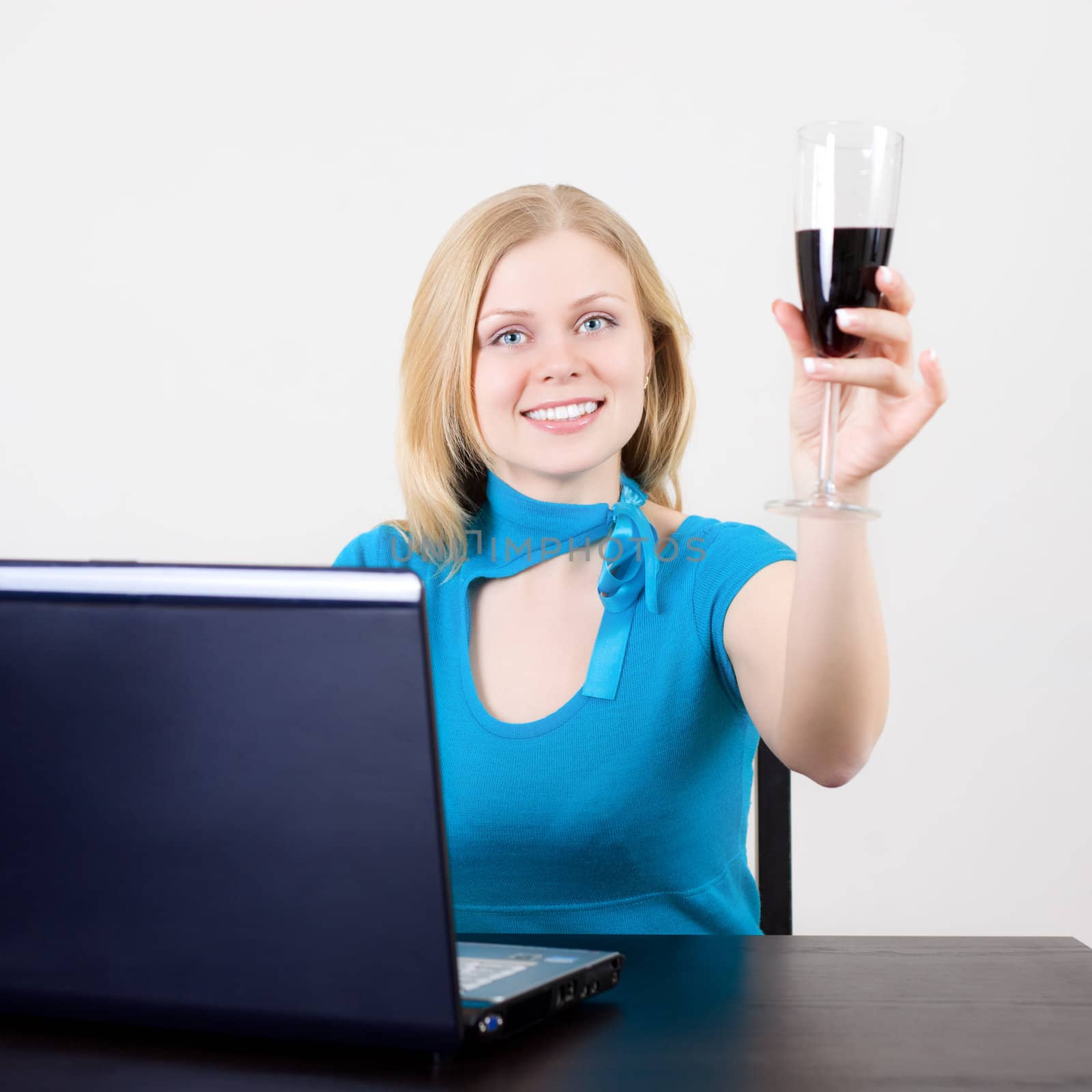business woman celebrating her success with wine in front of her computer