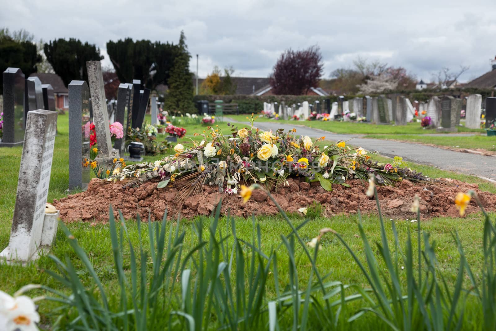 Flowers on the top of a newly dug burial site in graveyard
